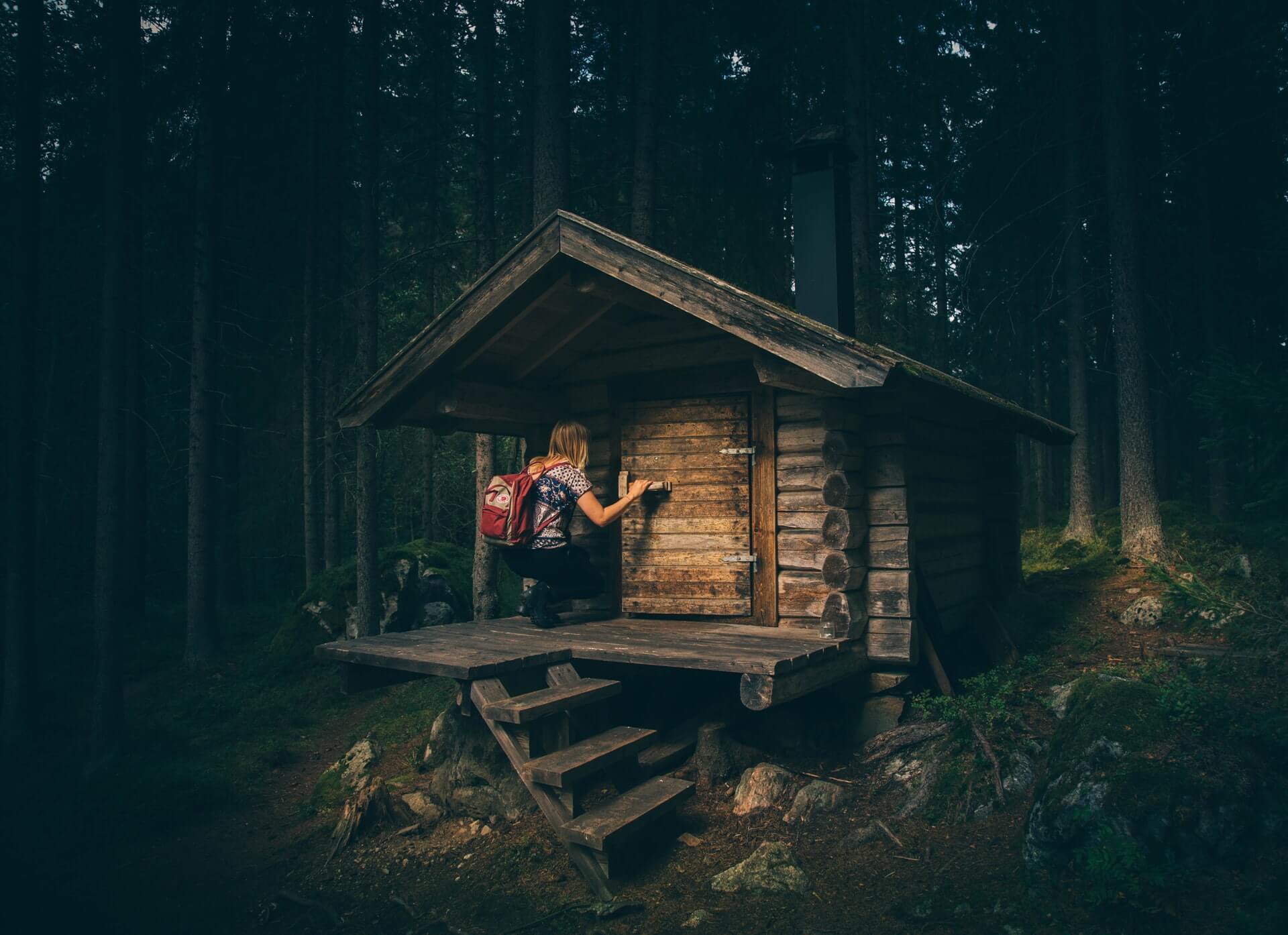 Foto på en liten stuga i skogen.